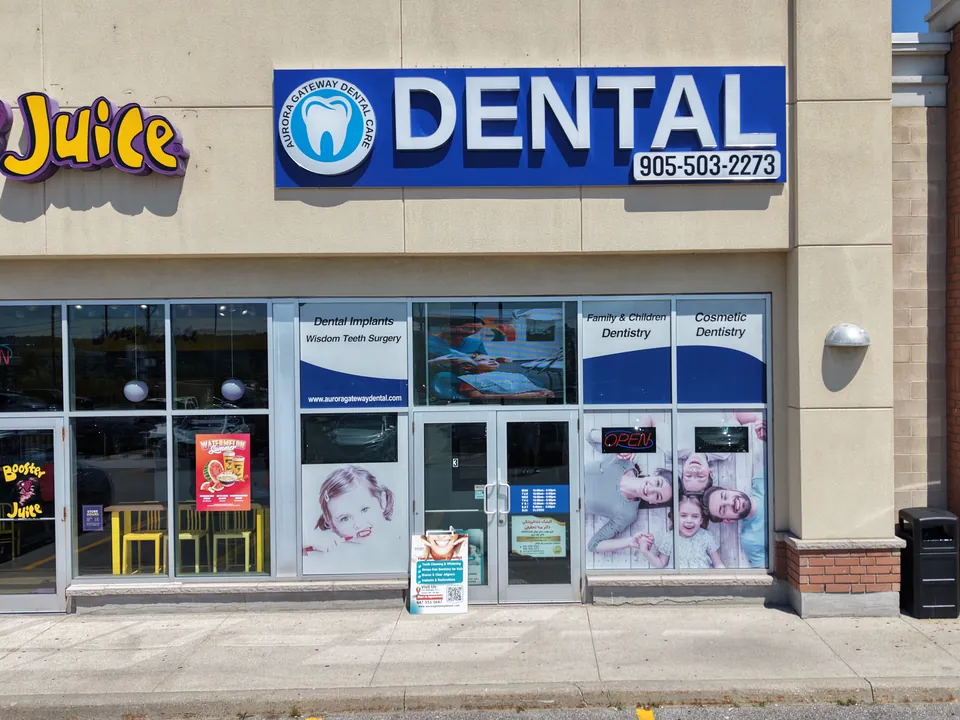 The clinic entrance under the blue DENTAL sign, with parking in front