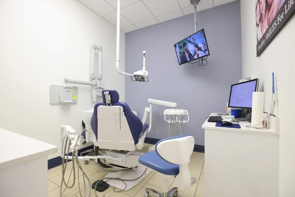 A treatment room with a dental chair and ceiling screen