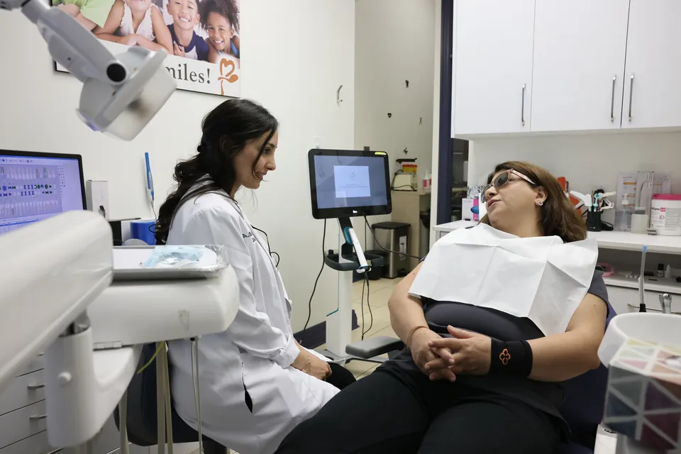 A dentist checks on a patient in the treatment chair