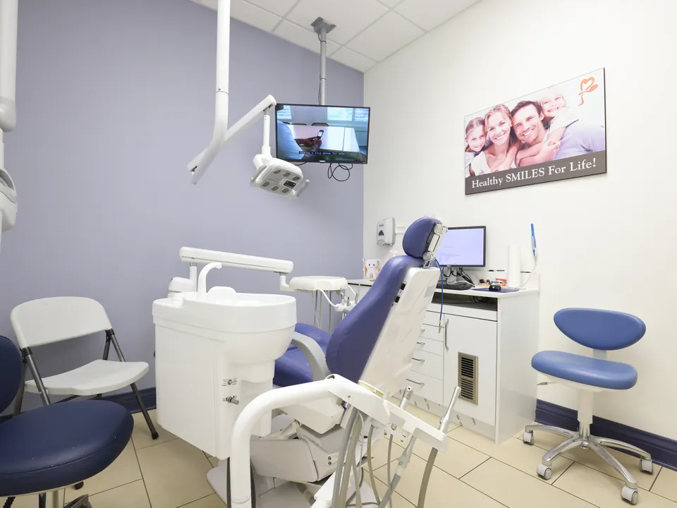 A bright treatment room with a children's smile poster on the wall